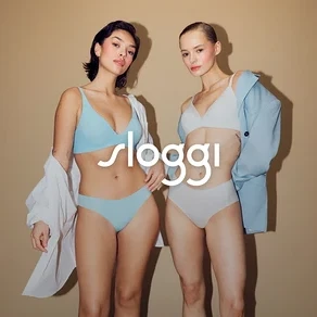 Dwie kobiety pozują w bieliźnie na beżowym tle. Jedna kobieta ma na sobie jasnoniebieską bieliznę, a druga jasną bieliznę.