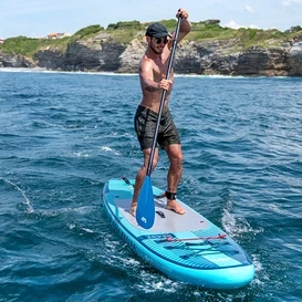 Mężczyzna wiosłuje na niebieskiej desce Aqua Marina SUP »Beast« 10'6" na morzu.