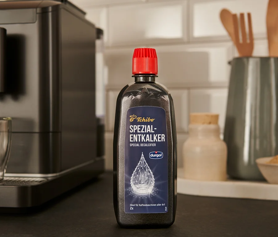 Czarna butelka specjalistycznego odkamieniacza durgol® 400 ml stoi na blacie obok ekspresu do kawy.