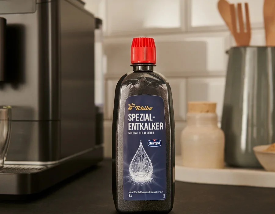 Czarna butelka specjalistycznego odkamieniacza durgol® 400 ml stoi na blacie obok ekspresu do kawy.