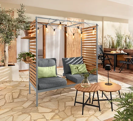 Szara sofa ScanCom Outdoor z podnóżkiem na tarasie.