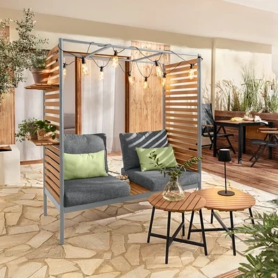 Szara sofa ScanCom Outdoor z podnóżkiem na tarasie.