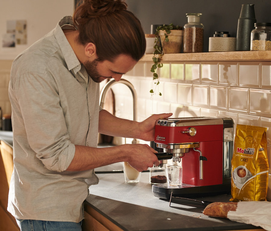 Mężczyzna przygotowuje kawę w czerwonym ekspresie kolbowym do kawy »Lapressa«.