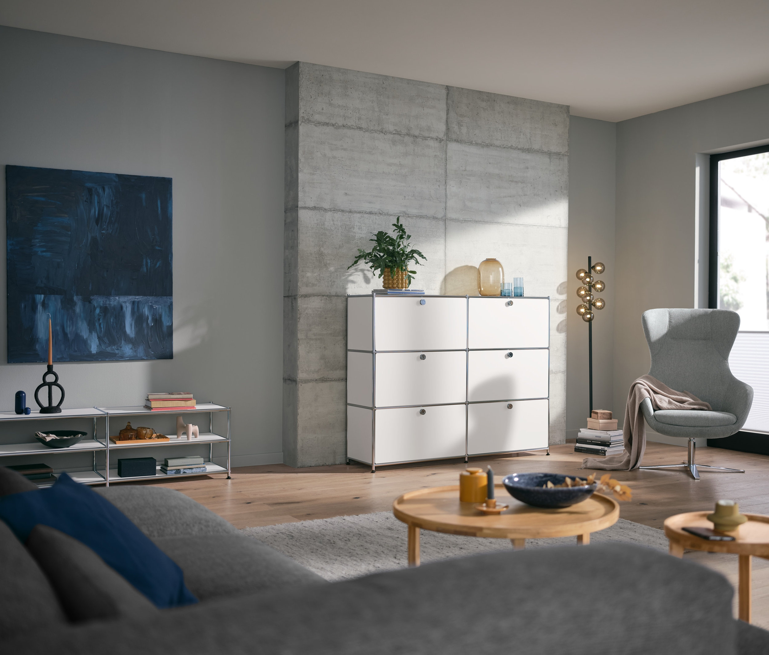 Pokój dzienny z okrągłym stolikiem i białą metalową komodą »CN3« z 6 komorami z klapami.