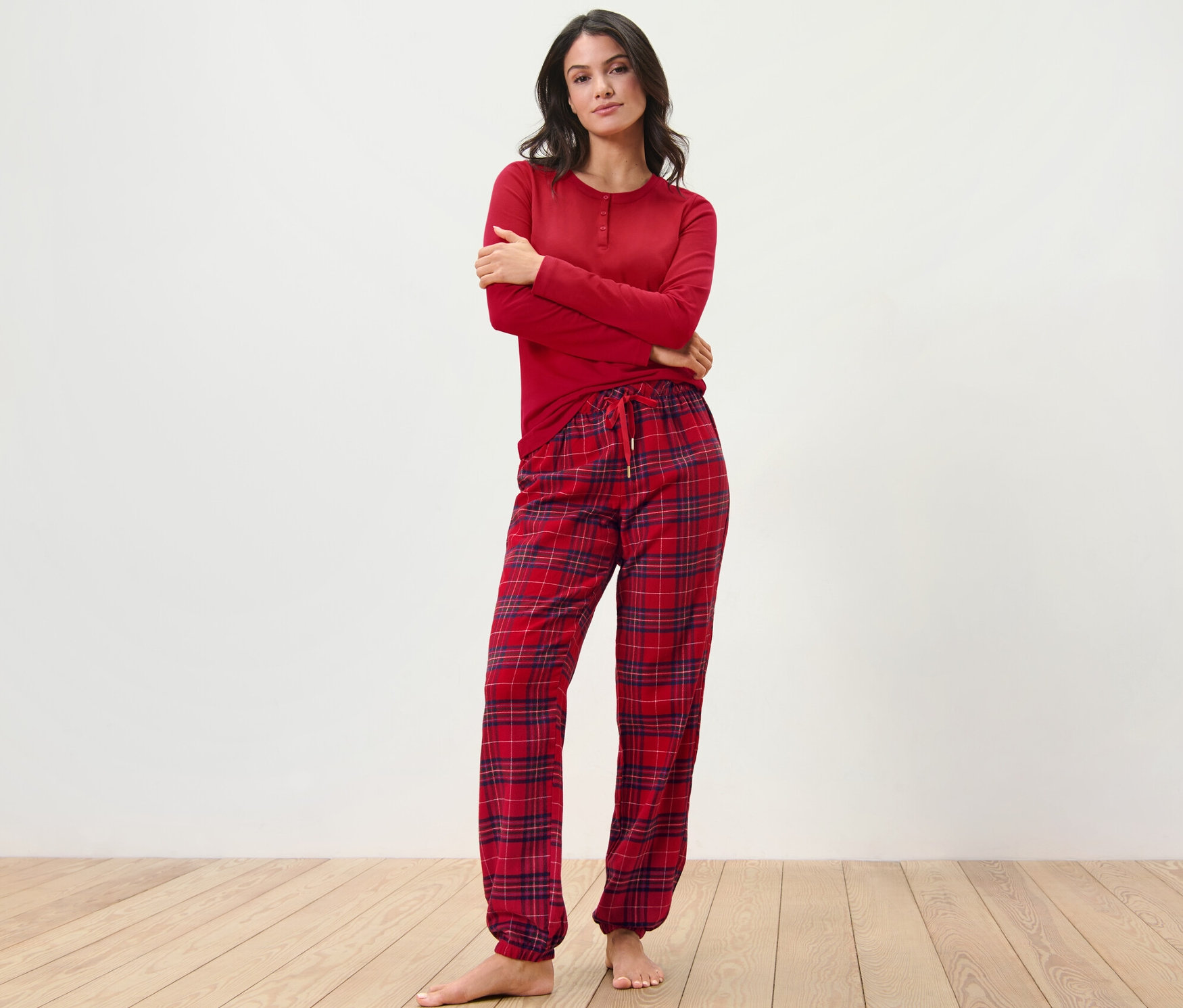Kobieta pozuje w czerwonej, flanelowej piżamie w kratę.