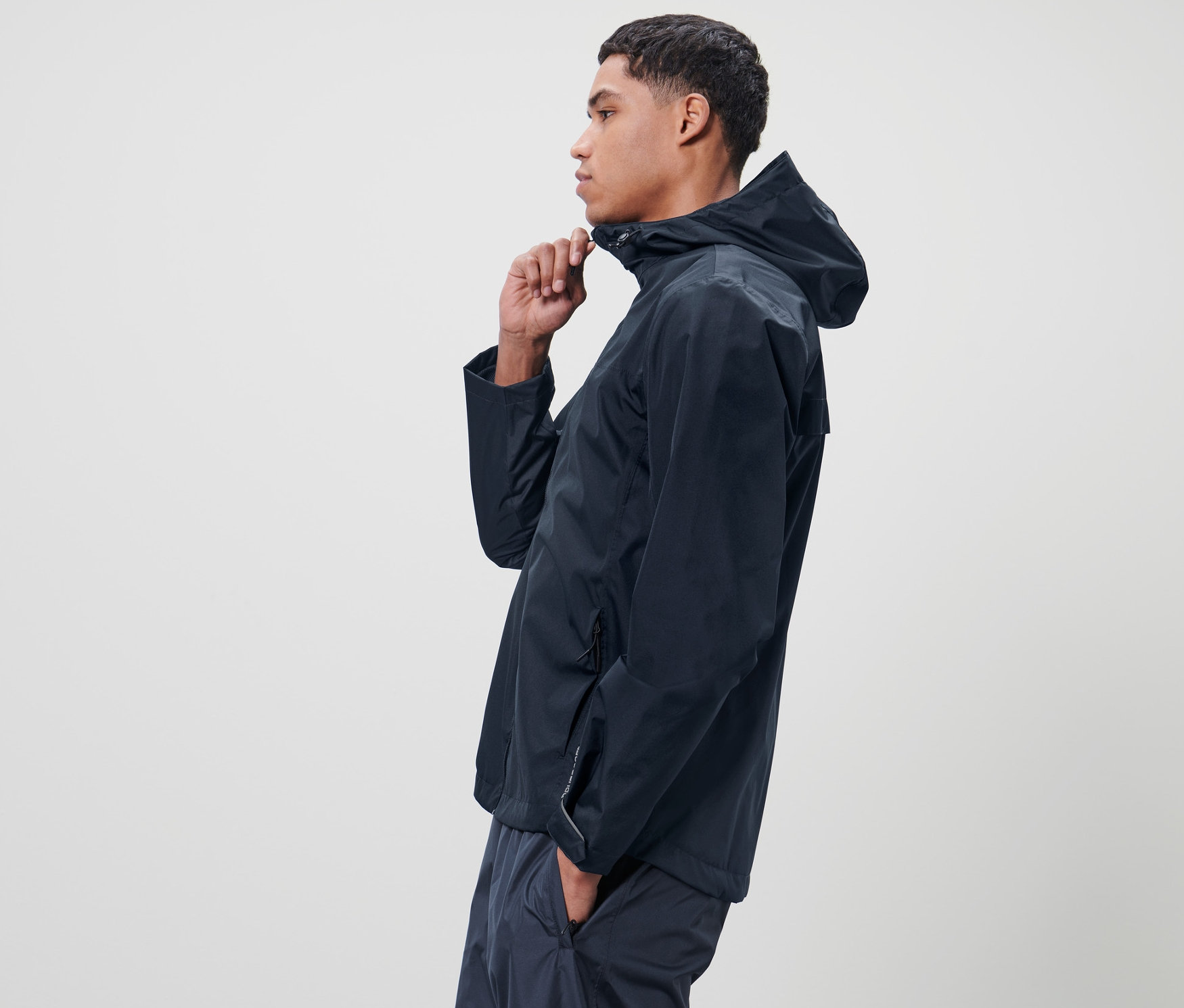 Mężczyzna zapina niebieską kurtkę przeciwdeszczową unisex.