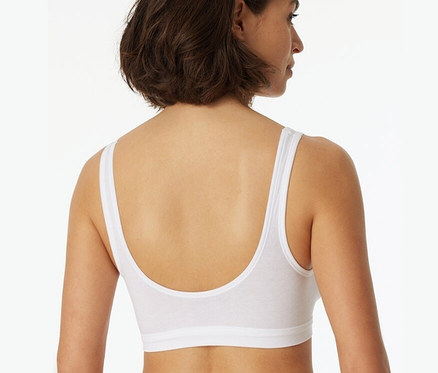 Widok z tyłu na kobietę z brązowymi włosami, ubraną w białe braletki z miseczkami i bawełną ekologiczną SCHIESSER, 2 sztuki.