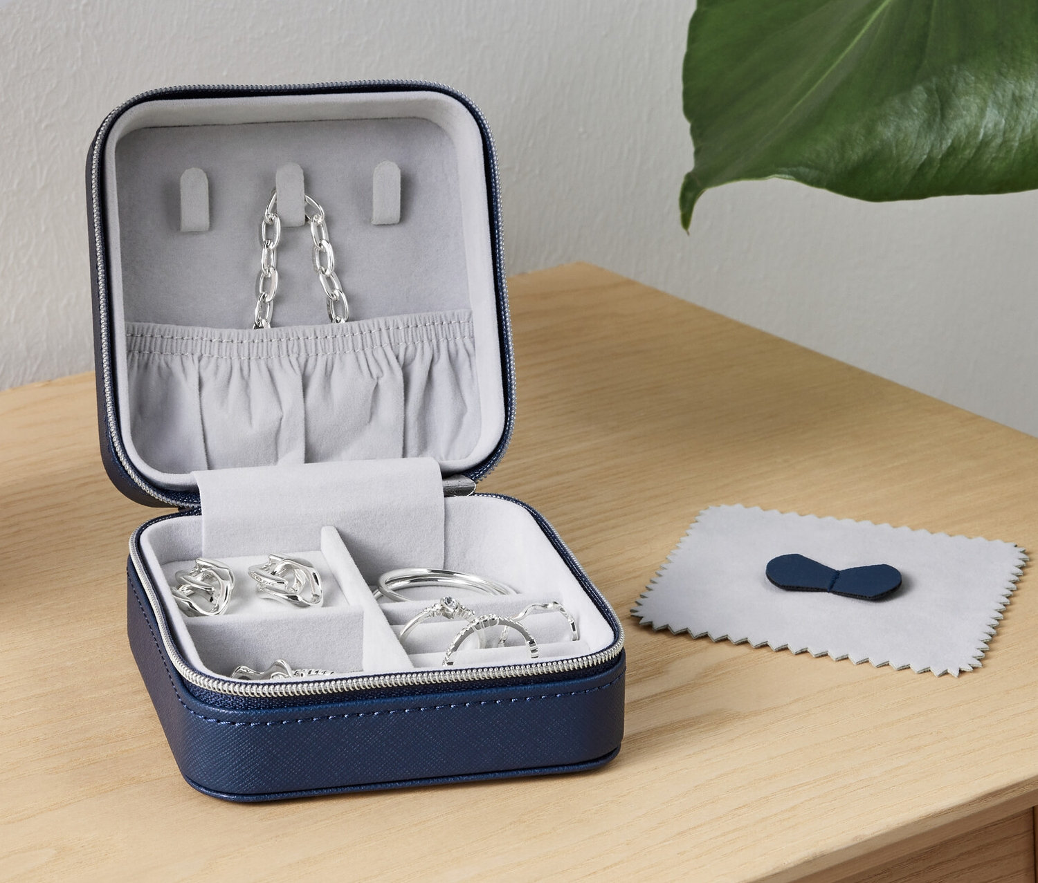 Otwarte małe pudełko na biżuterię z biżuterią w środku stoi na stole obok lampy.