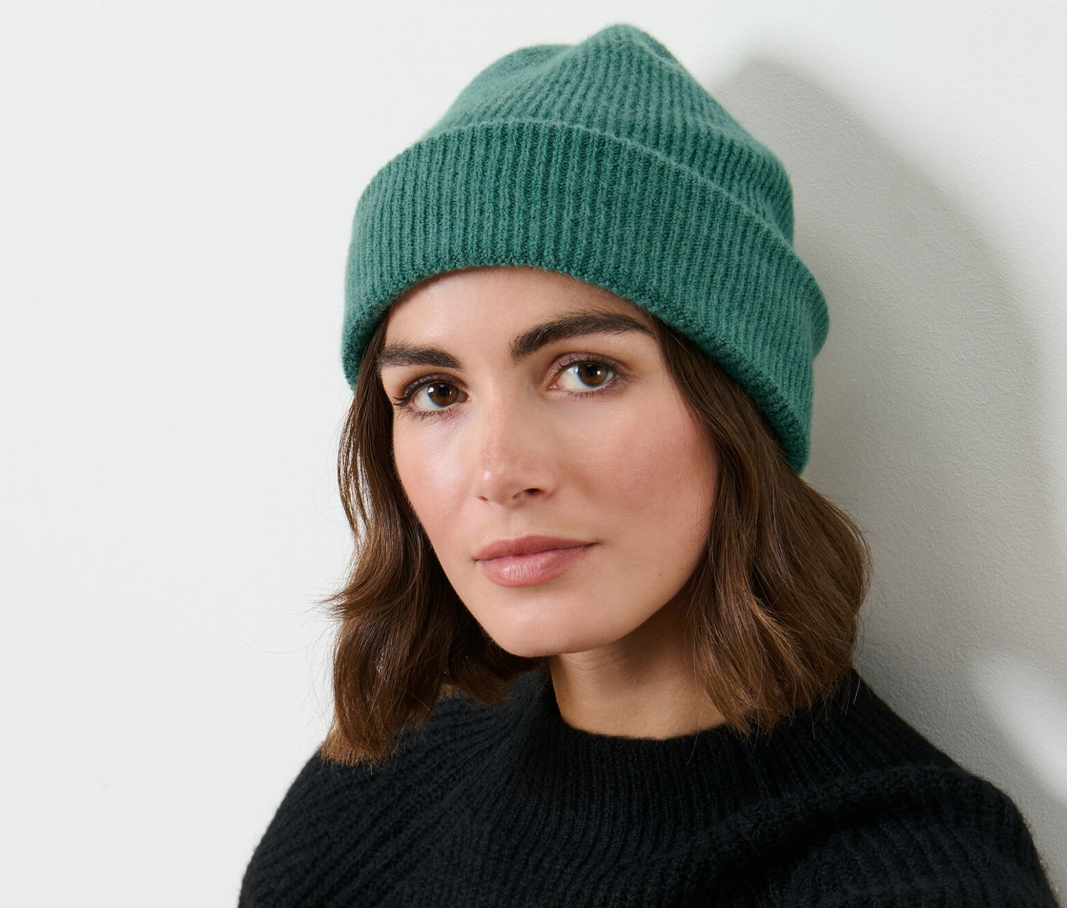 Kobieta nosi zieloną czapkę z dzianiny.