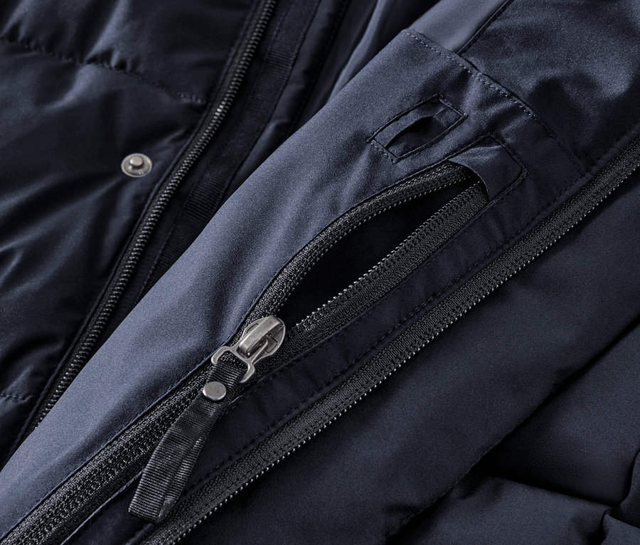 Zbliżenie na granatową pikowaną parkę z kapturem, zamek błyskawiczny i guziki.