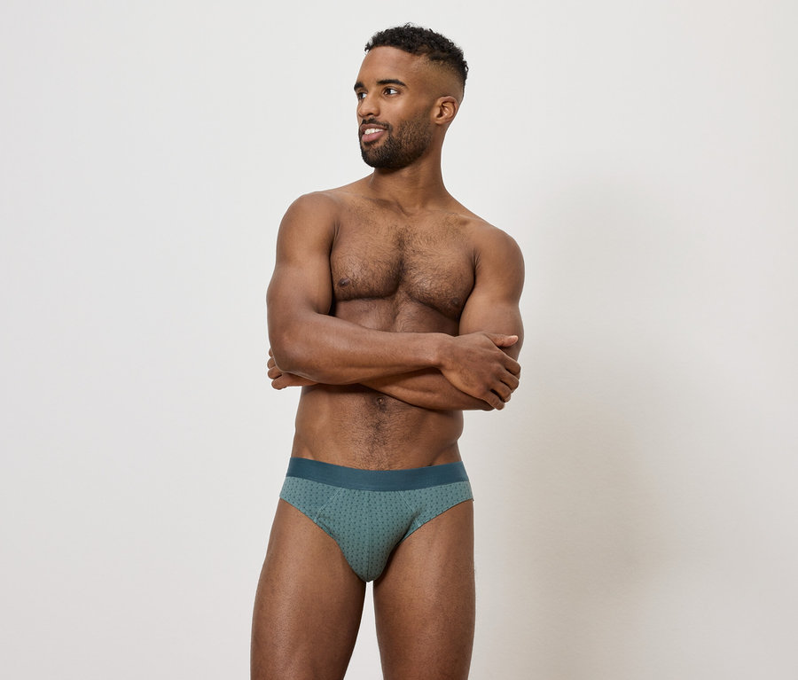 Mężczyzna ze skrzyżowanymi rękami na piersi, ubrany w zielone slipy.