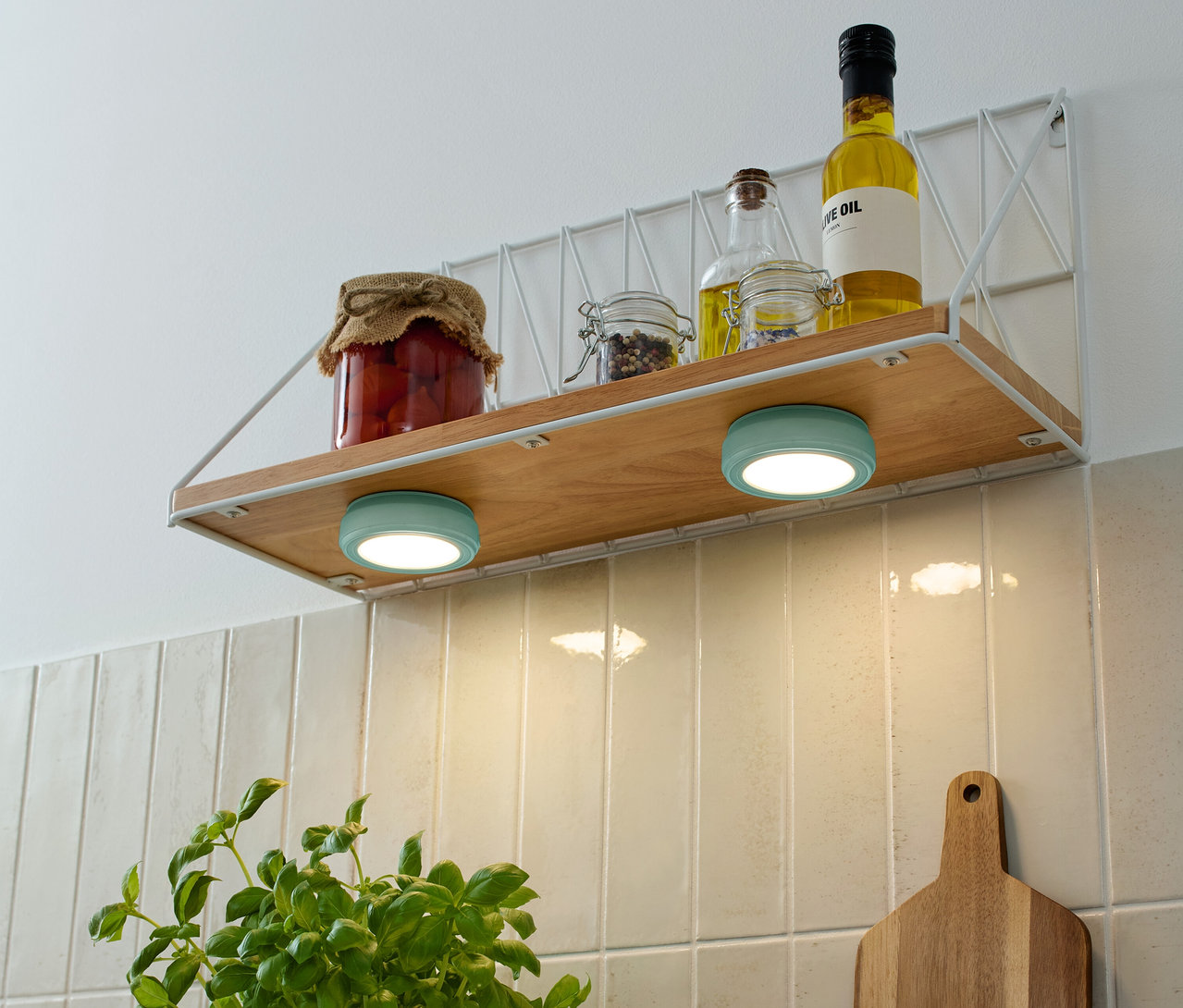 Na półce stoją słoiki z zapasami i butelki z olejem, a pod nimi dwie turkusowe 2 LED-Multifunktionsleuchten.