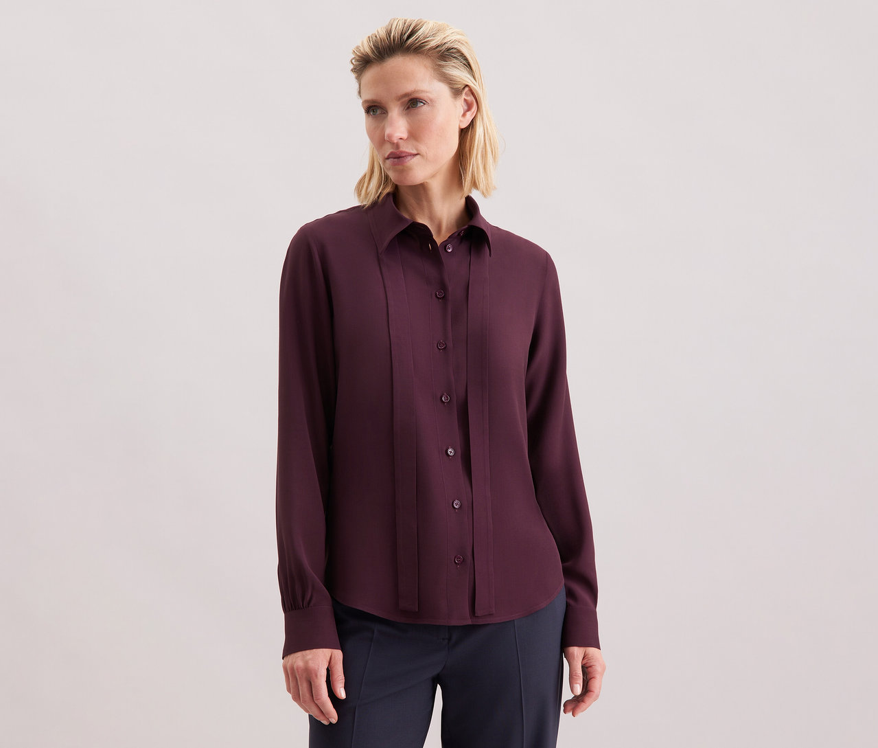 Kobieta ma na sobie bluzkę z wiskozy Seidensticker, bordową, z guzikami.