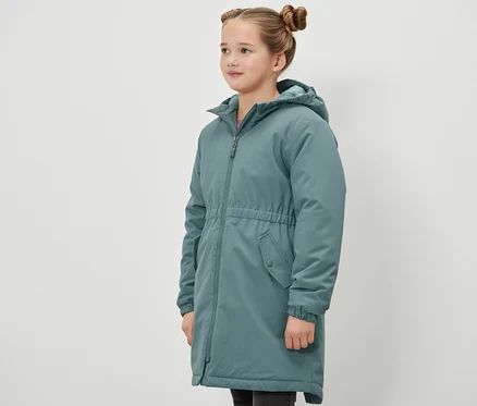 Dziewczyna stoi bokiem i ma na sobie zieloną parkę termiczną Kinder-Thermoparka.