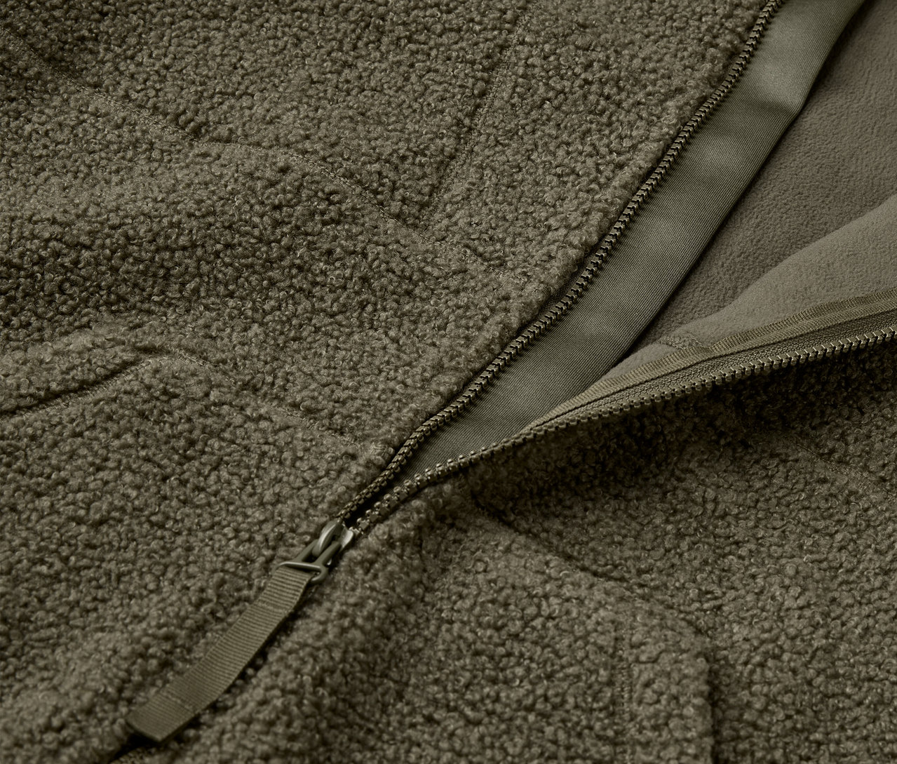 Zdjęcie zbliżeniowe oliwkowo zielonej, puszystej kurtki z zamkiem błyskawicznym.