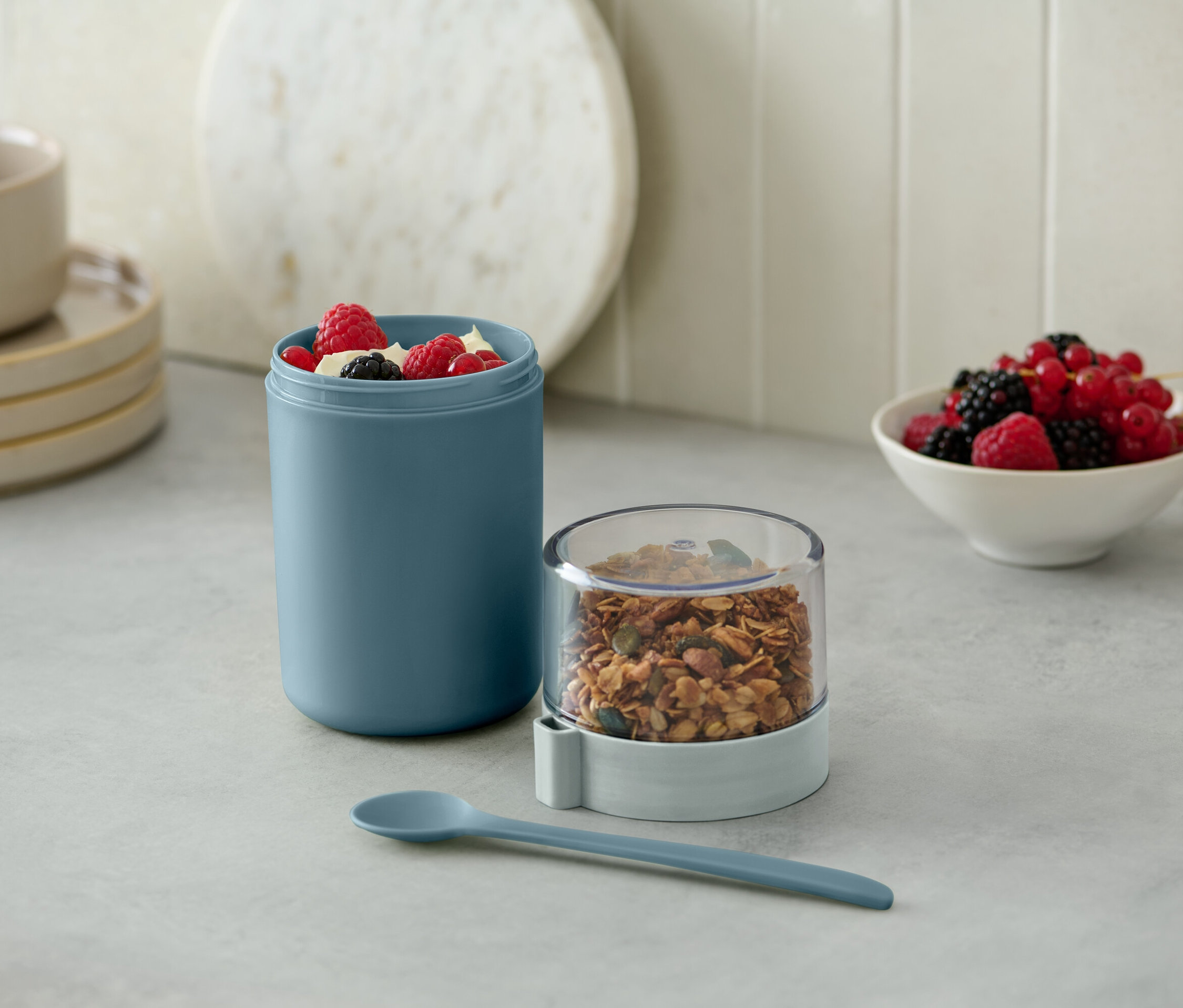 Zielony kubek na jogurt to go z musli i jagodami.