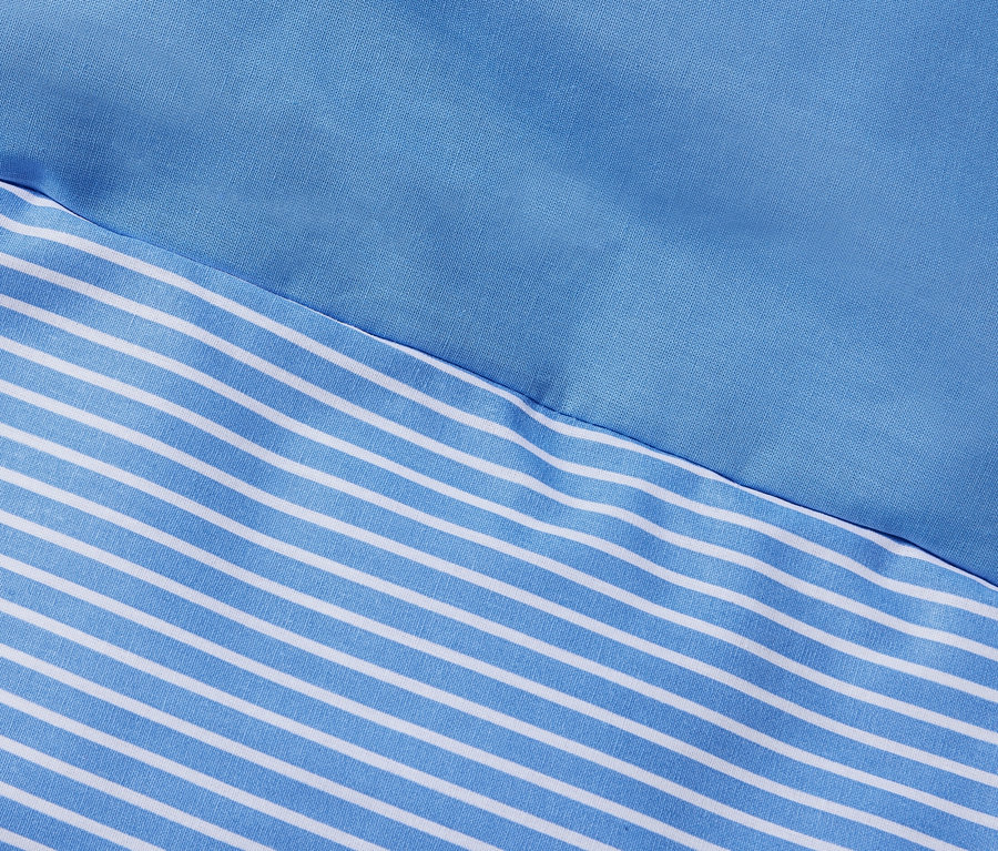 Zbliżenie na niebiesko-białą pościel z bawełny renforcé w paski.