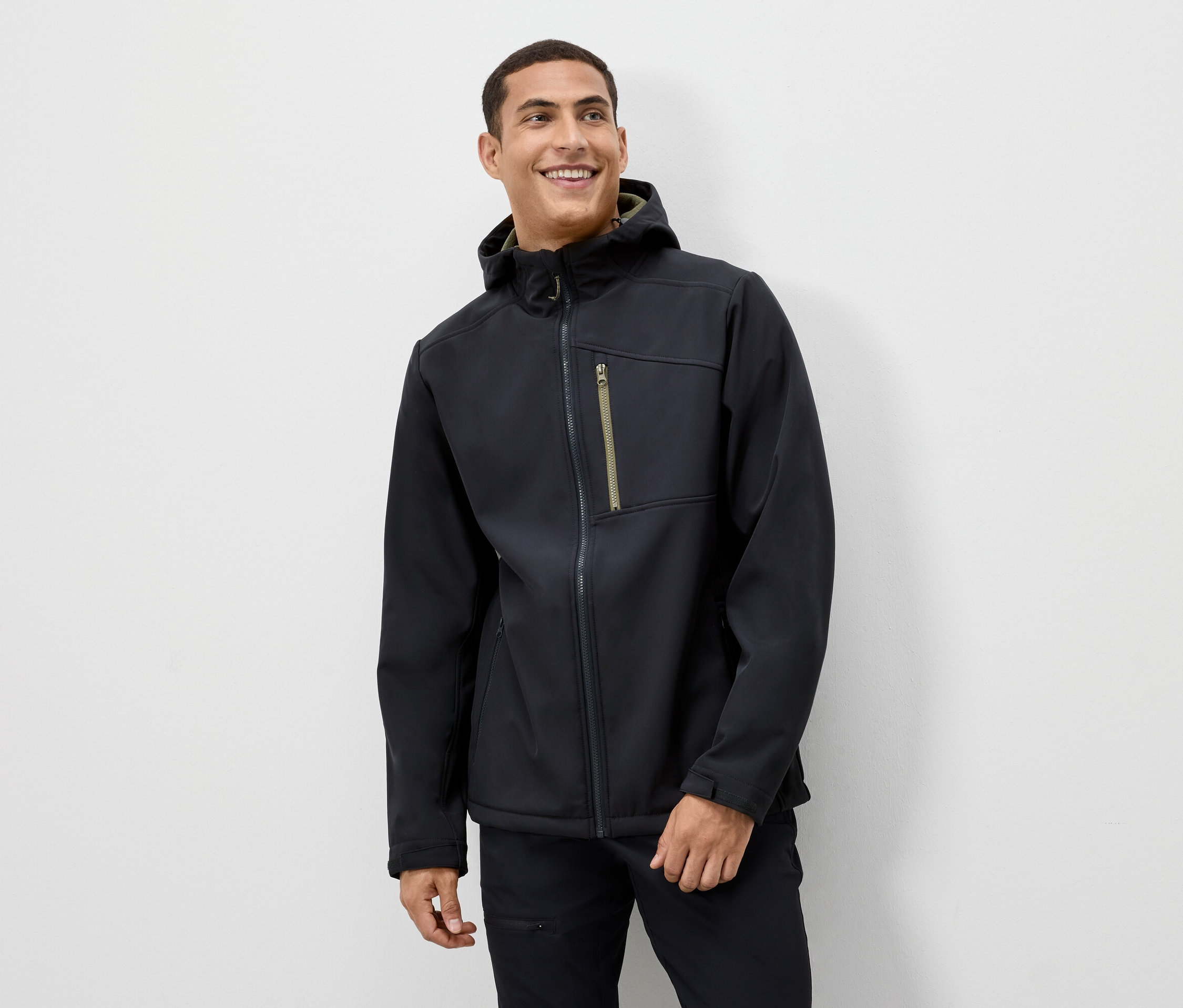 Mężczyzna uśmiecha się, ma na sobie czarną kurtkę z kapturem.