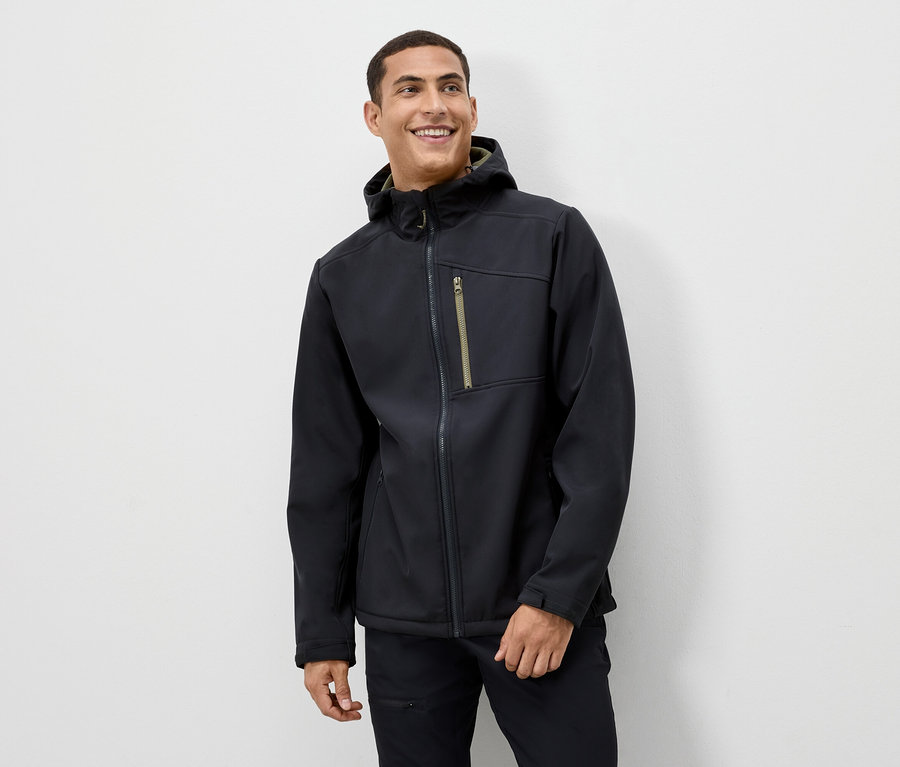 Mężczyzna uśmiecha się, ma na sobie czarną kurtkę z kapturem.