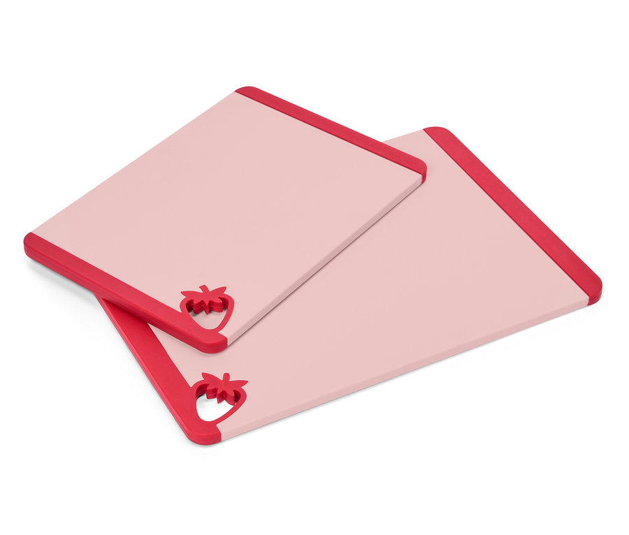 Dwie prostokątne, różowe deski do krojenia z czerwonymi akcentami w kształcie truskawek w jednym rogu leżą jedna na drugiej.
