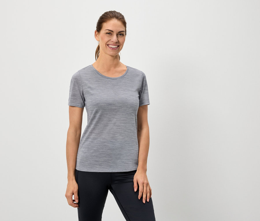 Kobieta ma na sobie szary T-shirt i czarne legginsy.