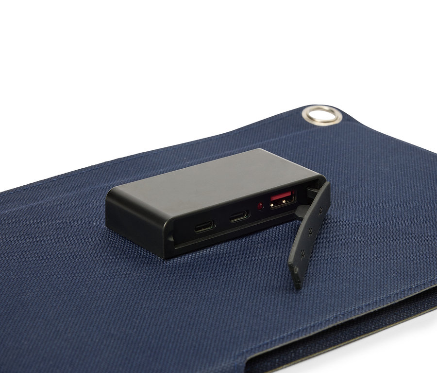Czarny akumulator leży na niebieskiej powierzchni materiału, z widocznym portem USB.