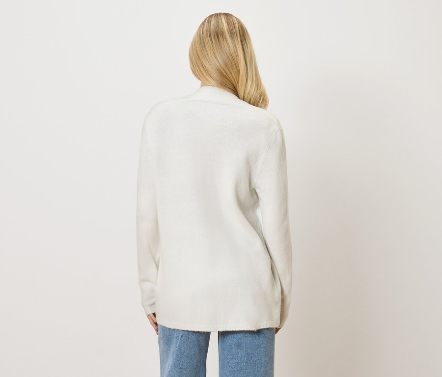 Widok z tyłu kobiety z blond włosami w białym kardiganie i dżinsach.