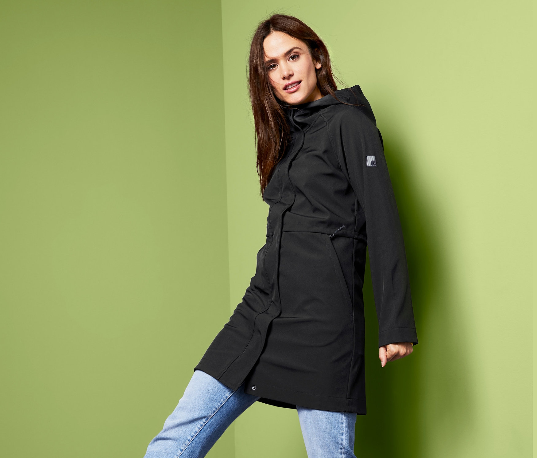 Kobieta pozuje w czarnym płaszczu softshell.