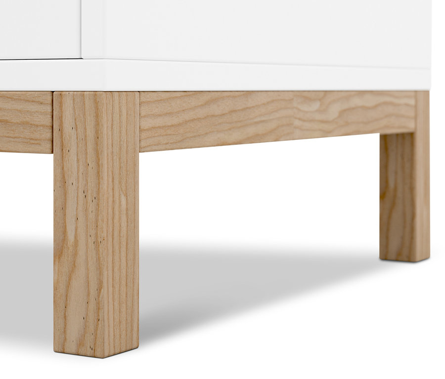 Szczegół białego kredensu z drewnianymi nogami.