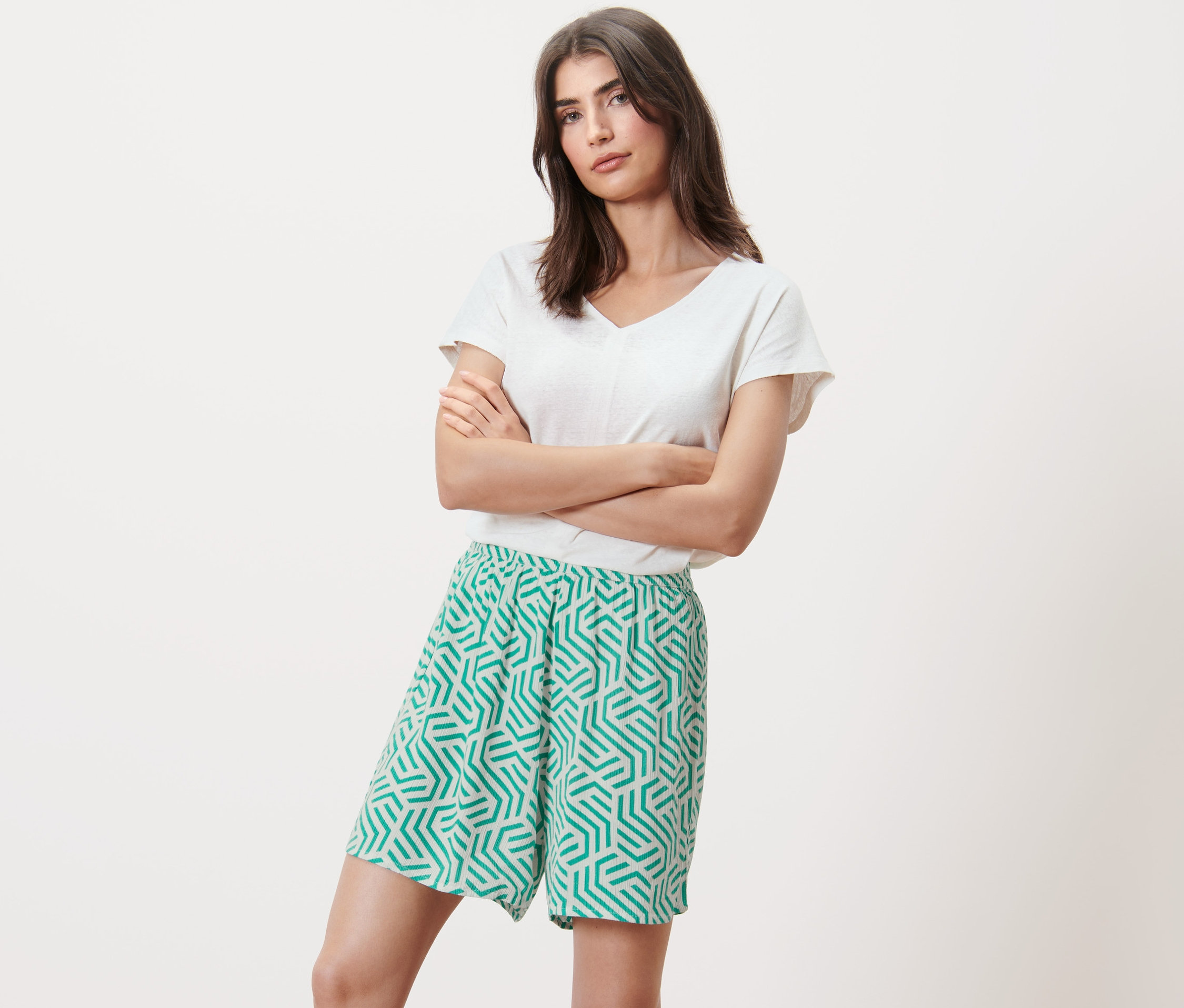 Kobieta pozuje ze skrzyżowanymi ramionami w szortach z tkaniny z nadrukiem.