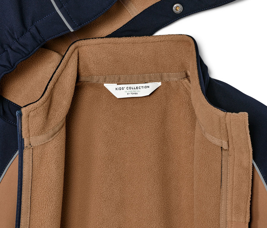 Zbliżenie na dziecięcą kurtkę softshell z brązową podszewką z polaru.