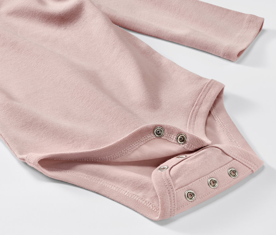 Zbliżenie na różowe body z długim rękawem dla niemowląt z 5-częściowego zestawu.