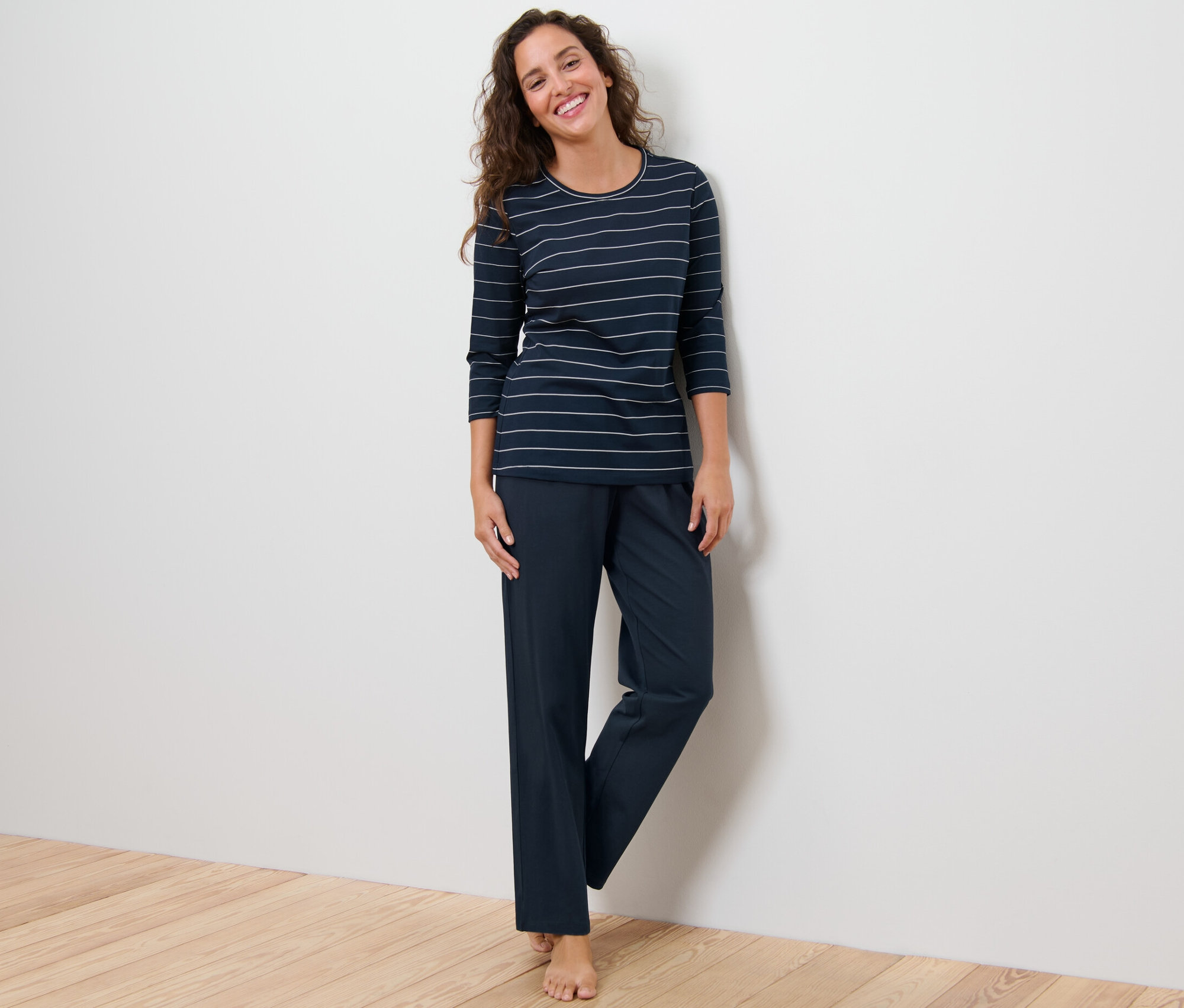 Kobieta stoi i ma na sobie piżamę w paski.