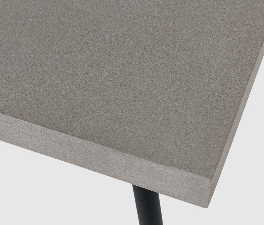 Zbliżenie na stolik kawowy z blatem z policementu i czarnymi nogami.