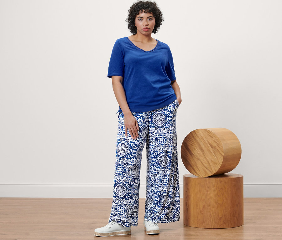 Kobieta pozuje w kobaltowej koszulce i spodniach palazzo z nadrukiem.