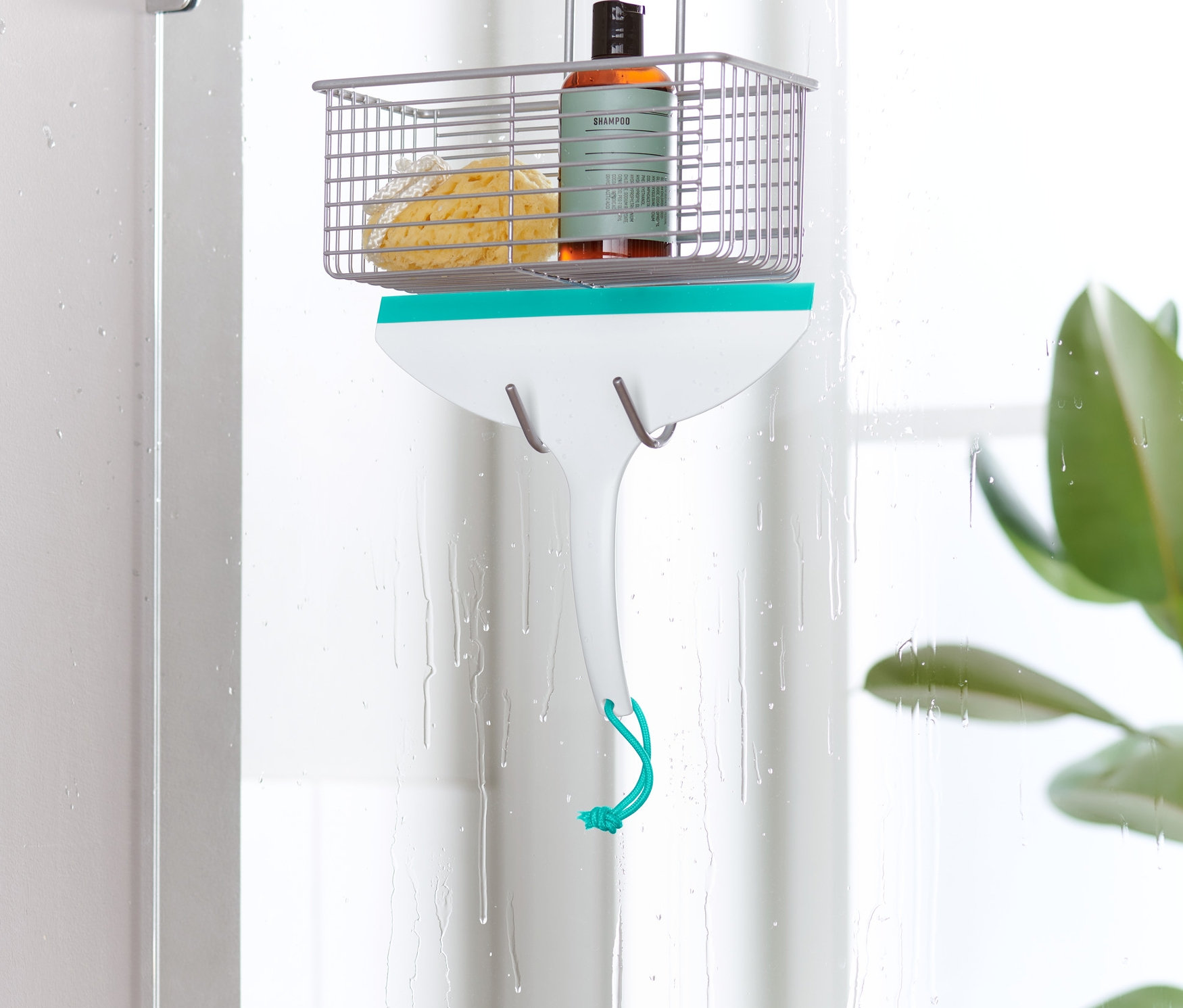 Ściągaczka do wody wisi na drzwiach kabiny prysznicowej.