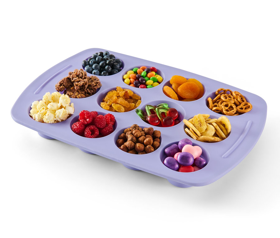 Fioletowa składana silikonowa forma do muffinów wypełniona jagodami, płatkami śniadaniowymi, cukierkami, morelami, preclami, popcornem, malinami, orzechami, wiśniami, chipsami bananowymi i słodyczami.