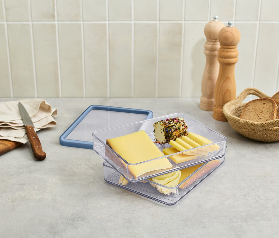 Pojemnik na wędliny i sery z serami i wędlinami na stole.