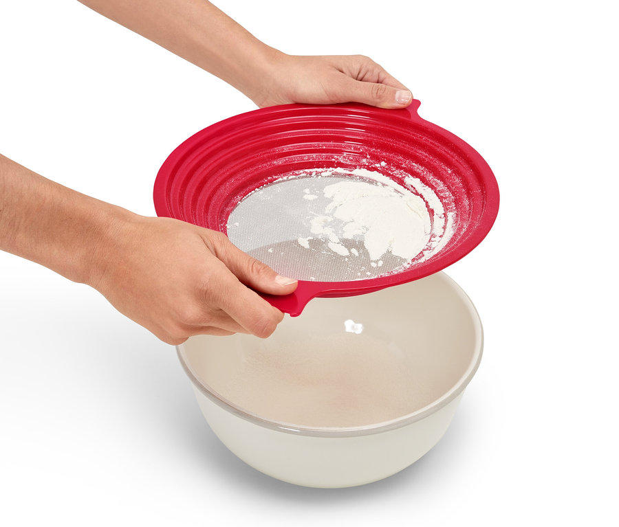 Osoba przesiewa mąkę przez czerwone sitko 2 w 1 do miski.