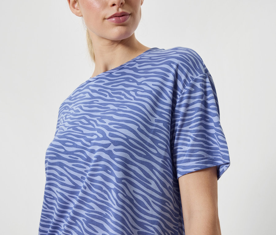 Kobieta ma na sobie niebieską koszulkę we wzór zwierzęcy.