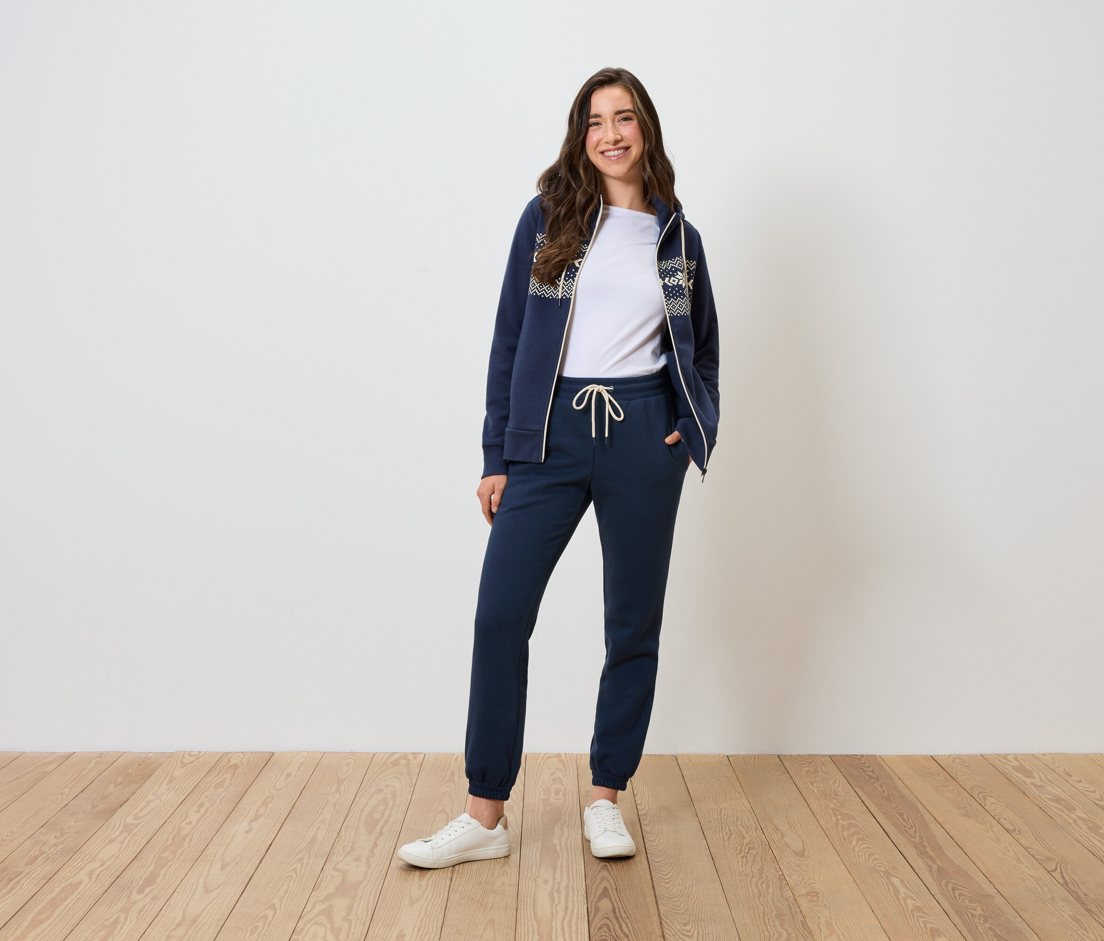 Kobieta pozuje w granatowym dresie i białym T-shircie.