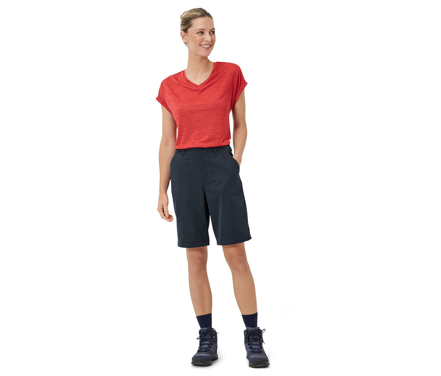 Kobieta stoi w czerwonej koszulce i granatowych spodniach funkcyjnych 2 w 1.