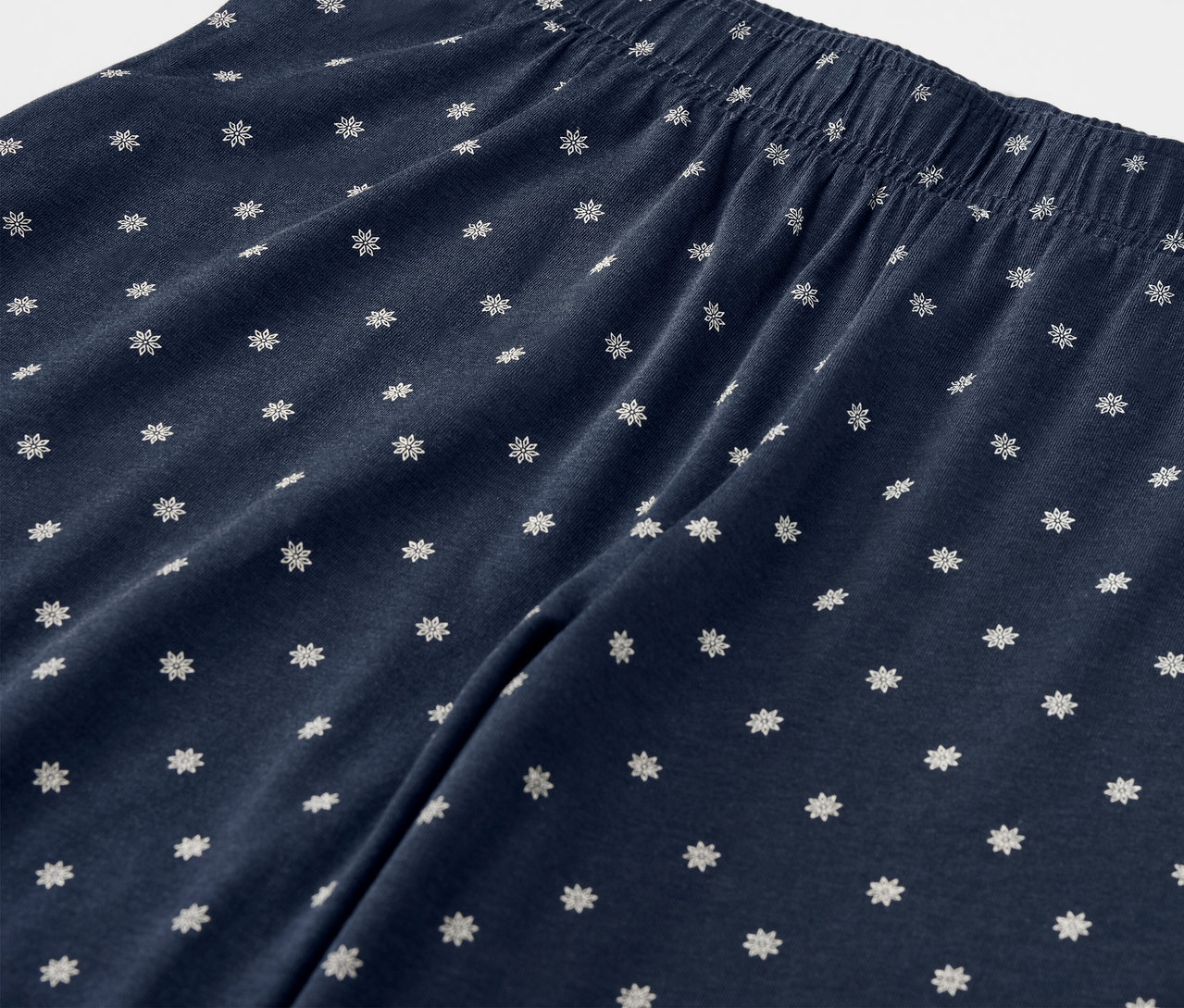 Zbliżenie na granatowe spodnie z białymi kwiatami i elastycznym pasem.