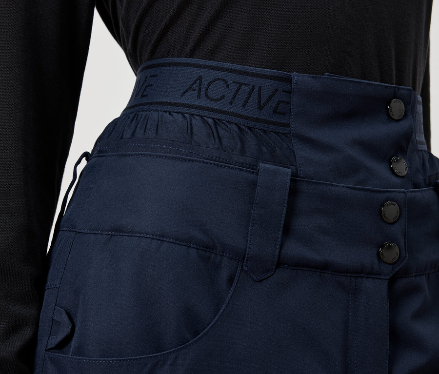 Zbliżenie na granatowe spodnie z wysokim stanem i guzikami.