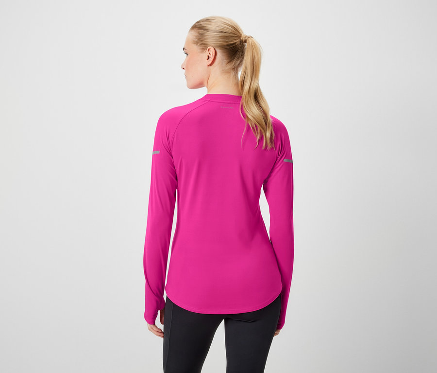 Widok z tyłu kobiety z blond włosami związanymi w koński ogon, ubranej w różową bluzkę z długim rękawem i czarne legginsy.