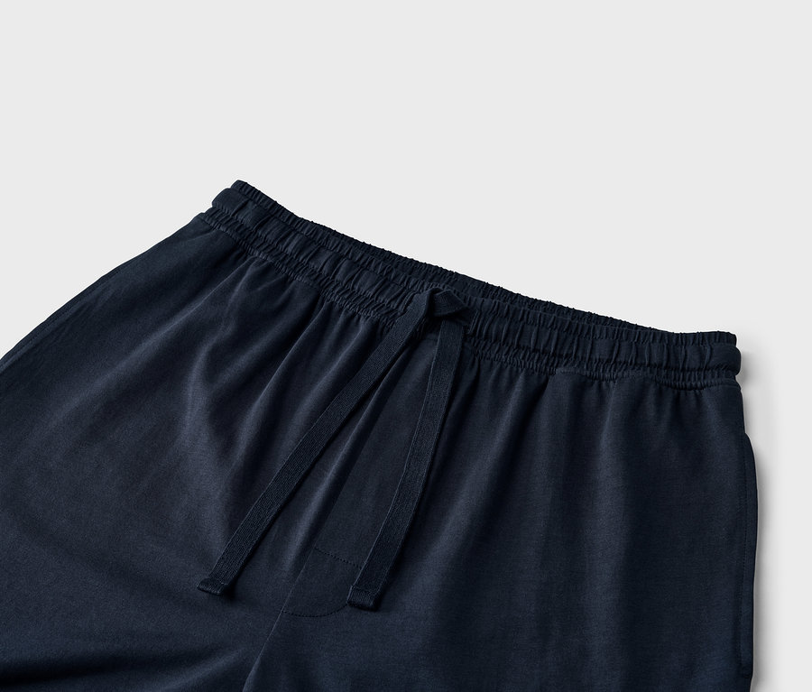 Szczegół granatowych spodni dresowych ze sznurkiem w pasie.