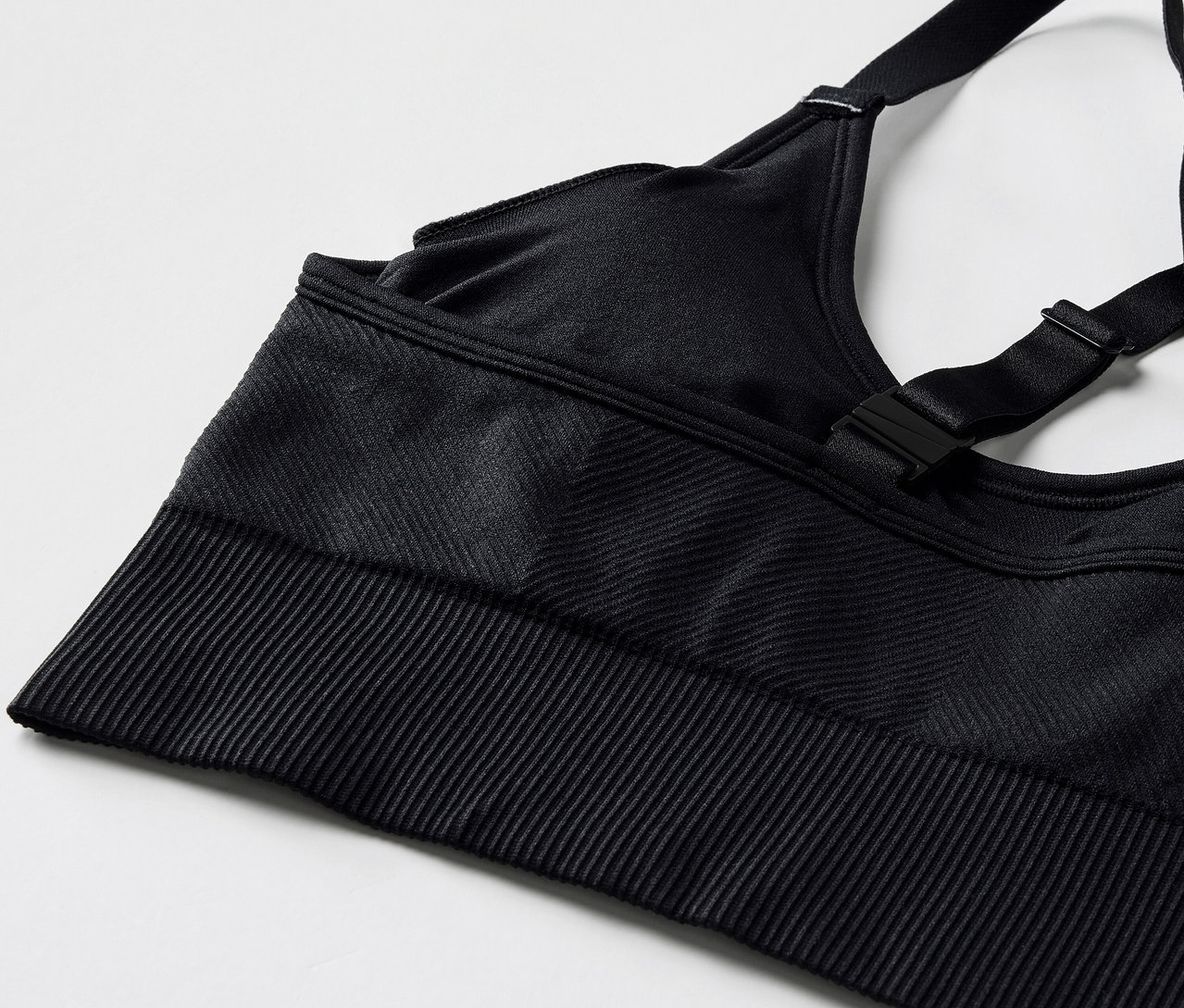 Szczegółowe ujęcie czarnego stanika sportowego z regulowanymi ramiączkami i prążkowanym dołem.