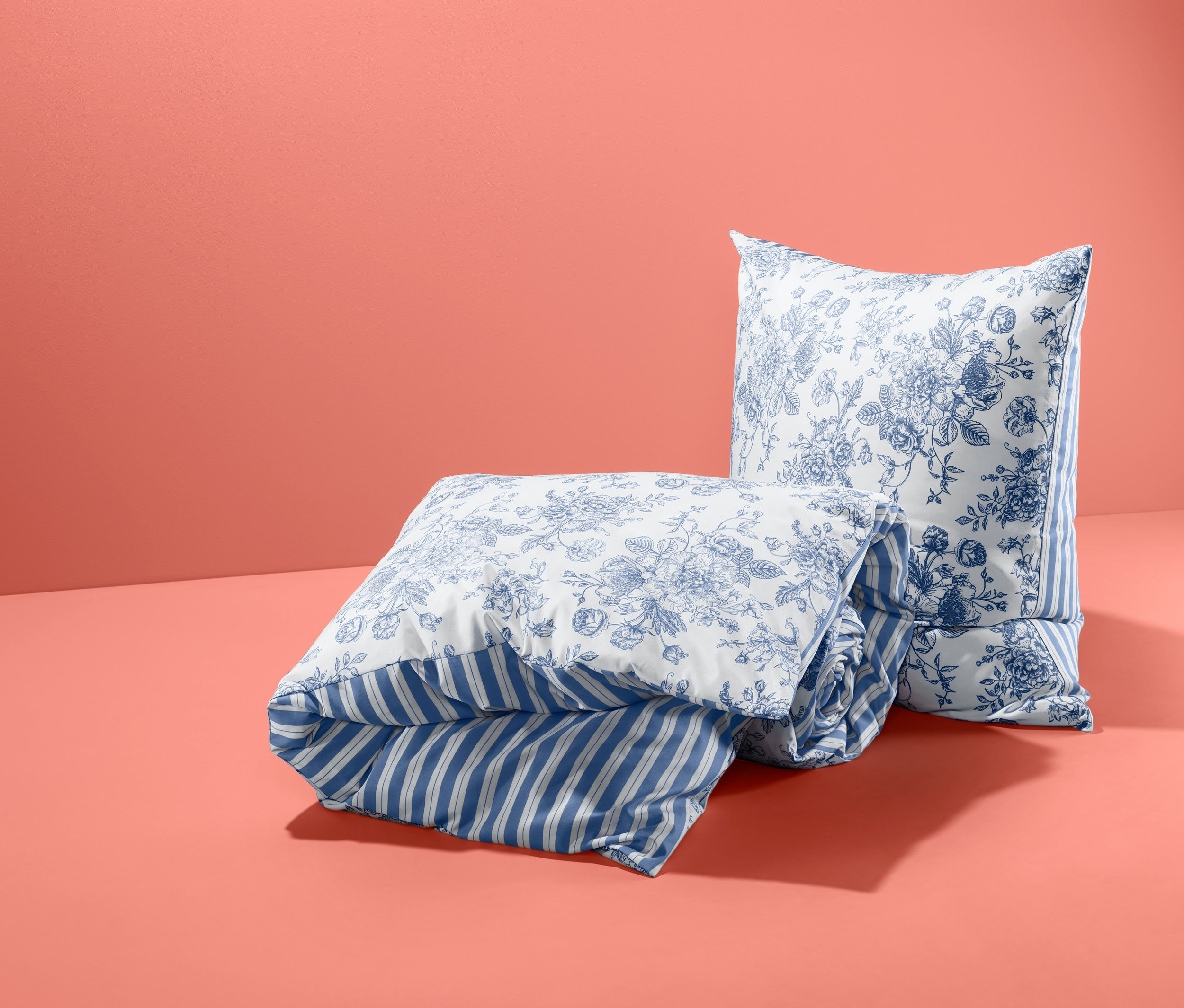 Złożona dwustronna pościel ze wzmocnionej bawełny, wielkość podwójna i poduszka we wzory kwiatowe na koralowym tle.