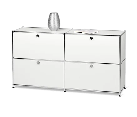 Biała metalowa szafka typu sideboard „CN3” z 4 klapami. Na szafce stoi srebrny wazon i otwarta książka.