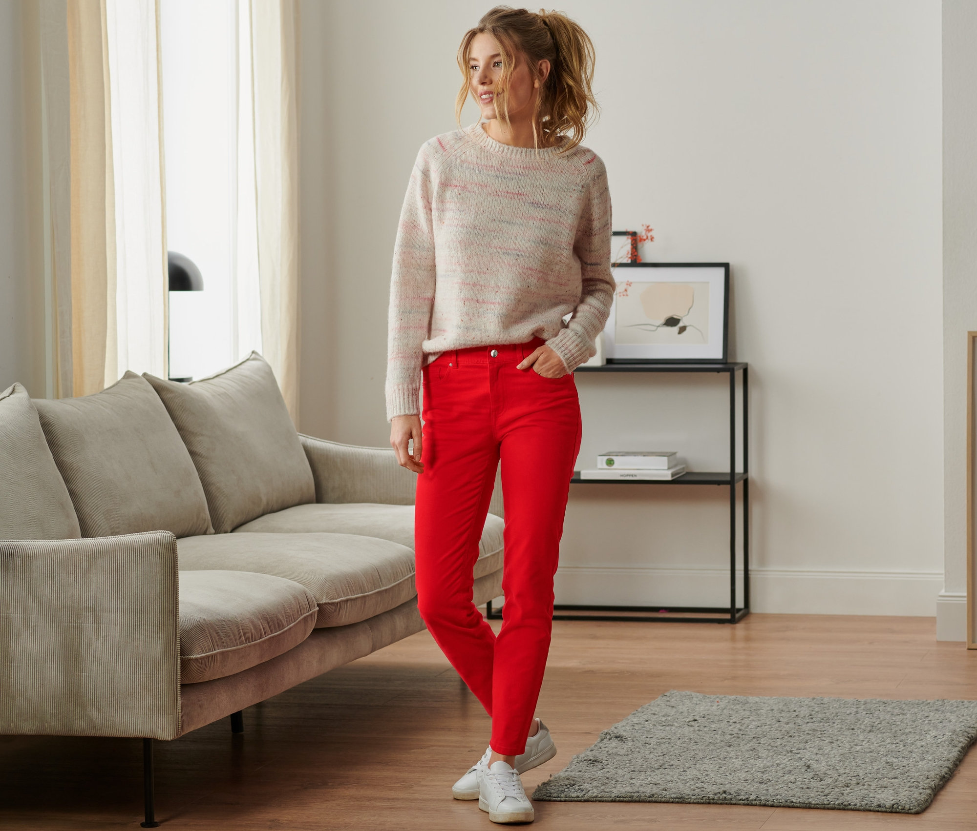 Kobieta stoi w salonie i ma na sobie spodnie dżinsowe.